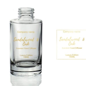 Könnte beinhalten: Eine durchsichtige Glasflasche mit einem goldenen Etikett, auf dem "Company name Sandalwood & Oak Scented Reed Diffuser Luxury Edition 150ML" steht.