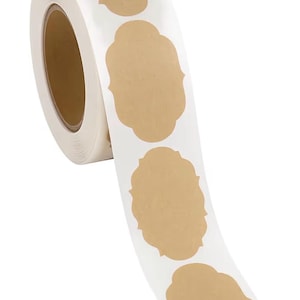 以下が含まれることがあります： 白紙ラベルのロールで、ベージュ色の装飾的な形のステッカーが繰り返されています。 ロールは部分的にほどかれ、いくつかのステッカーが現れています。 これらのラベルは、工芸品、包装、または整理に適しています。