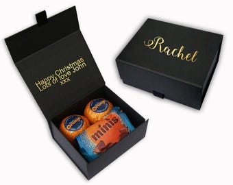 May include: Black gift box with a gold inscription that reads "Happy Christmas Lots of love John xxx". The box is open and contains a small box of chocolates with a gold inscription that reads "minis".