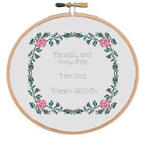 May include: White embroidery hoop with a floral design in shades of green and pink. The text "Be still, and know that I am God. Psalm 46:10a" is embroidered in the center.