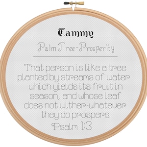 May include: A cross-stitch embroidery hoop with the name "Tammy" and the phrase "Palm Tree-Prosperity" in black text. The text includes a quote from Psalm 1:3. The hoop is made of light-colored wood.
