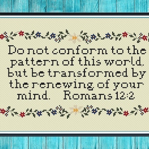 May include: Cross-stitch artwork in a black frame, with the text "Do not conform to the pattern of this world, but be transformed by the renewing of your mind. Romans 12:2." The design includes a floral border with red, blue, and yellow flowers.