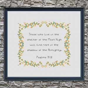 May include: Framed cross-stitch artwork with a navy blue frame. The text reads "Those who live in the shelter of the Most High will find rest in the shadow of the Almighty. Psalms 91:1" surrounded by a floral border.
