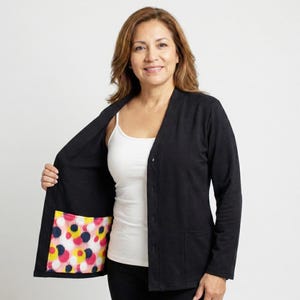 May include: A black cardigan with a V-neck and button fastening. The inside pocket lining has a colourful pattern of pink, yellow, blue, and black polka dots. The cardigan is worn over a white vest top.