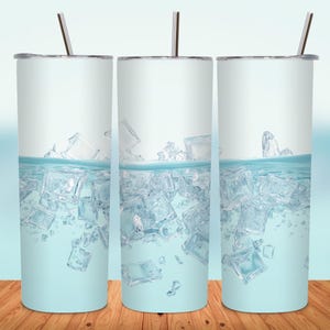 May include: Three stainless steel tumblers with a light blue design of ice cubes in water. Each tumbler has a silver lid and a silver straw. The tumblers are displayed on a wooden surface.