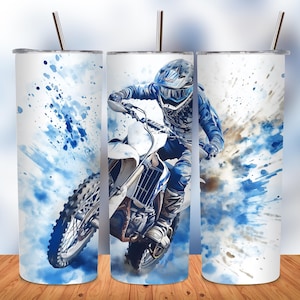 May include: A white and blue watercolour design on a stainless steel tumbler features a motocross rider in a blue and white racing suit, helmet, and goggles, riding a white dirt bike. The rider is in mid-air, with blue and white watercolour splashes behind them.
