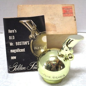 May include: Vintage gold-colored metal atomizer perfume bottle with a unique design.  The bottle is spherical with a curved spout.  Accompanying the bottle is its original box and an instruction booklet. The booklet features text: 