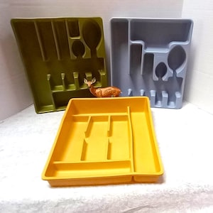 May include: Three plastic cutlery trays in different colors: yellow, green, and light blue. Each tray has compartments for different types of utensils.