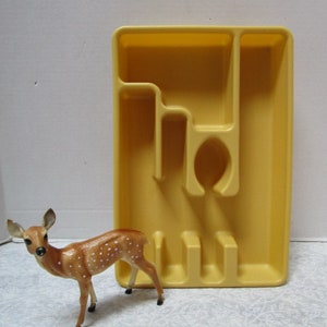 May include: A yellow plastic cutlery tray with five compartments. The tray has a raised edge around the perimeter and a smooth surface.