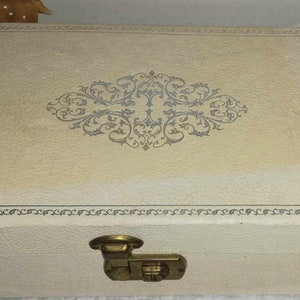May include: A white jewelry box with a decorative floral design and a brass latch.