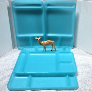 May include: A set of four bright turquoise plastic divided trays, each featuring a large rectangular section and two smaller square compartments, arranged with a small brown and white spotted deer figurine standing in the center of the display.