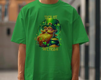 Puede incluir: Camiseta verde con un diseño del Día de San Patricio. El diseño incluye un duende con un sombrero verde, una larga barba amarilla y una olla de oro. También se muestra el texto "LUCK OF THE IRISH".