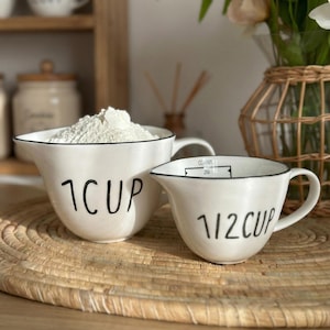 May include: A set of three ceramic canisters with lids. The canisters are white with a blue floral pattern. The largest canister is 20 cm tall, the medium is 15 cm, and the smallest is 10 cm.