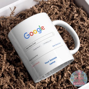 May include: White ceramic mug with the Google logo and a search bar that reads "Best Boss Ever." The mug includes the text "Your bosses name" and is presented in a gift box with brown paper filler.