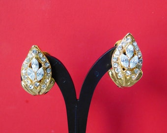 May include: A pair of gold tone clip-on earrings with clear rhinestone accents in a leaf design.