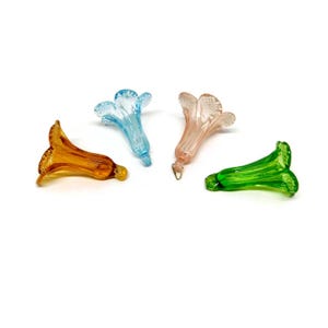 May include: Four glass flower charms in different colors: light blue, light pink, orange, and green. The charms are shaped like a flower with five petals and a long stem.