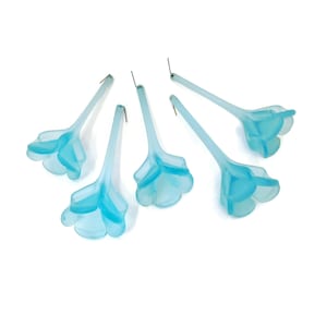 May include: Set of six light blue glass flower-shaped ornaments with a wire stem. The ornaments are frosted and have a delicate, feminine look.