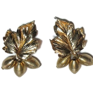 May include: Gold tone leaf earrings with three small gold tone beads dangling from each leaf.
