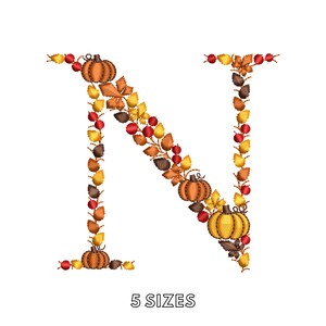 May include: An embroidered letter N formed by autumn-themed elements including orange pumpkins, red berries, and yellow, orange, and brown leaves. The design features a detailed stitched texture throughout the letter shape. The text 5 SIZES is below.