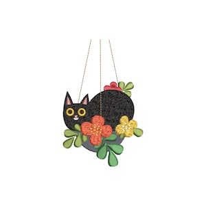 May include: A black cat-shaped embroidery with yellow eyes and a smiling face, surrounded by colorful flowers and green leaves. The cat is hanging from two brown strings, creating a whimsical, decorative piece.