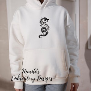 Puede incluir: Sudadera con capucha color crema con un dise&ntilde;o de drag&oacute;n negro en la parte delantera. La sudadera tiene un bolsillo de canguro y una capucha con cord&oacute;n. El texto "Marite's Embroidery Designs" est&aacute; impreso en la parte inferior.