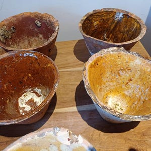 Könnte beinhalten: Vier Terrakotta-Töpfe mit brauner, orangefarbener und weißer Glasur. Die Töpfe sind in verschiedenen Größen und Formen und haben ein rustikales, handgemachtes Aussehen.