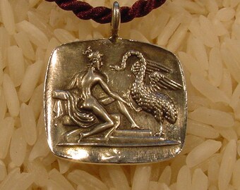 May include: A silver pendant necklace with a detailed image of a woman and a bird. The pendant is square shaped and has a textured surface.