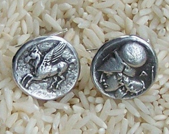 May include: A pair of silver earrings with a winged horse and a profile of a woman wearing a helmet on each earring.