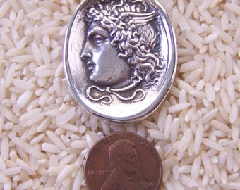 May include: Silver pendant necklace featuring a detailed profile of a winged goddess with a laurel wreath. The pendant is about the size of a US penny.
