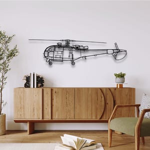 May include: A black metal helicopter wall art piece. The helicopter is a detailed outline, mounted on a white wall above a wooden cabinet. The design includes the rotor, tail, and body of the aircraft. Home decor.