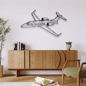 May include: A black metal airplane wall art piece. The artwork depicts a detailed outline of a private jet, showcasing its wings, engines, and fuselage. The piece is mounted on a white wall, adding a modern touch to the decor.