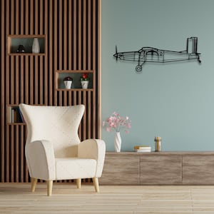 May include: A black metal airplane wall decor with a minimalist design, hanging on a light blue wall in a living room setting. The airplane is above a white armchair with a wood frame and a wooden cabinet with drawers.
