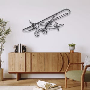 Peut inclure: Décoration murale en métal noir représentant un avion. L'avion, avec hélice et ailes, est fixé sur un mur blanc au-dessus d'un meuble en bois. Le design de l'avion est minimaliste, de style dessin au trait, pour une ambiance moderne.