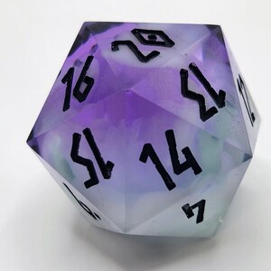 May include: A purple and green iridescent d20 dice with black numbers. The numbers on the dice are 1, 2, 3, 4, 5, 6, 7, 8, 9, 10, 11, 12, 13, 14, 15, 16, 17, 18, 19, and 20.