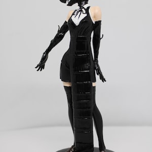 Könnte beinhalten: Schwarze Figur einer humanoiden Figur mit einer einzigartigen Kopfform, die ein schwarzes Kleid mit weißem Kragen, lange Handschuhe und Oberschenkelstrümpfe trägt. Die Figur steht auf einem schwarzen, kreisförmigen Sockel mit braunen Schuhen.
