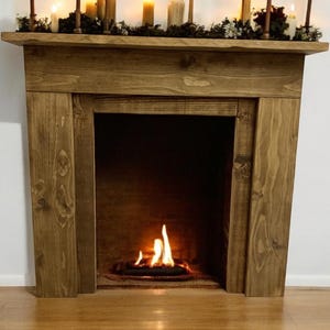 May include: A rustic wooden fireplace mantel with a black metal firebox and a small fire burning inside. The mantel is stained a dark brown colour and has a simple design.
