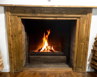 May include: A rustic wooden fireplace mantel with a roaring fire inside. The mantel is made of reclaimed wood and has a natural finish. The fire is burning brightly and casting a warm glow on the surrounding area.