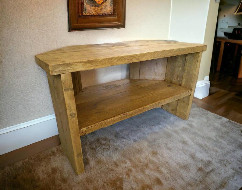 May include: A rustic wooden corner TV stand with a single shelf. The stand is made of reclaimed wood and has a natural finish.