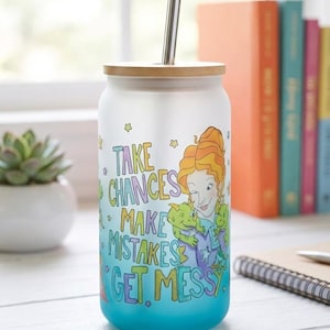 Può includere: Un bicchiere di vetro con coperchio in bambù e cannuccia in acciaio inossidabile. Il bicchiere presenta un design colorato con il testo "TAKE CHANCES MAKE MISTAKES GET MESSY" e un'illustrazione di una donna e due creature verdi.