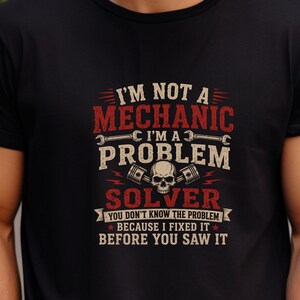 Peut inclure: Un t-shirt noir avec une impression graphique en texte rouge et beige qui dit : I'M NOT A MECHANIC I'M A PROBLEM SOLVER YOU DON'T KNOW THE PROBLEM BECAUSE I FIXED IT BEFORE YOU SAW IT, accompagné d'illustrations de deux clés et d'un crâne.