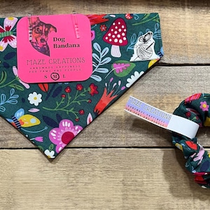 May include: A dog bandana and scrunchie set with a floral and mushroom pattern in shades of green, pink, yellow, and white. The bandana has a pink tag that says "Dog Bandana" and "Maze Creations". The scrunchie has a matching pattern.