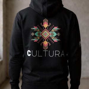 May include: Black hoodie with a geometric design in shades of pink, green, and brown on the back. The word "CULTURA" is printed in white below the design. The hoodie has a hood and is worn by a person.
