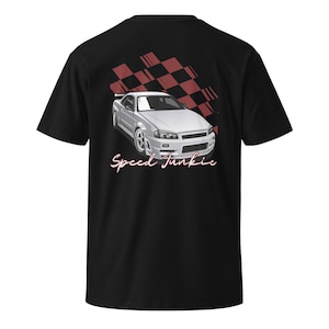 May include: Black t-shirt featuring a silver sports car graphic with the text "Speed Junkie" in a cursive font. A red and black checkered flag design is in the background. The shirt is a classic crew neck style.