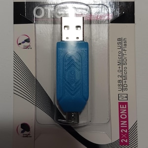 以下が含まれることがあります： 片側にマイクロUSBコネクタ、もう片側に標準USBコネクタが付いた青いUSBアダプター。アダプターには「2x2 IN ONE」と「USB 2.0 + Micro USB SD + Micro SD/T-Flash」のラベルが貼られています。