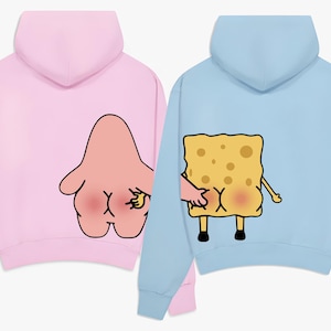 Op de afbeelding: Twee hoodies, een roze en een lichtblauwe. De roze hoodie heeft een cartoon Patrick Star-personage met een hand op zijn achterste. De blauwe hoodie heeft een cartoon SpongeBob SquarePants-personage met een hand op zijn achterste.