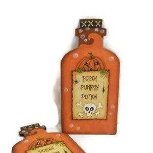 May include: Two orange wooden pumpkin potion bottles with a skull and crossbones and the text "Poison Pumpkin Potion" on a white background.