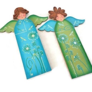 May include: Two wooden angel figurines with wings, painted in shades of blue and green. The angels have floral designs and dragonfly accents.