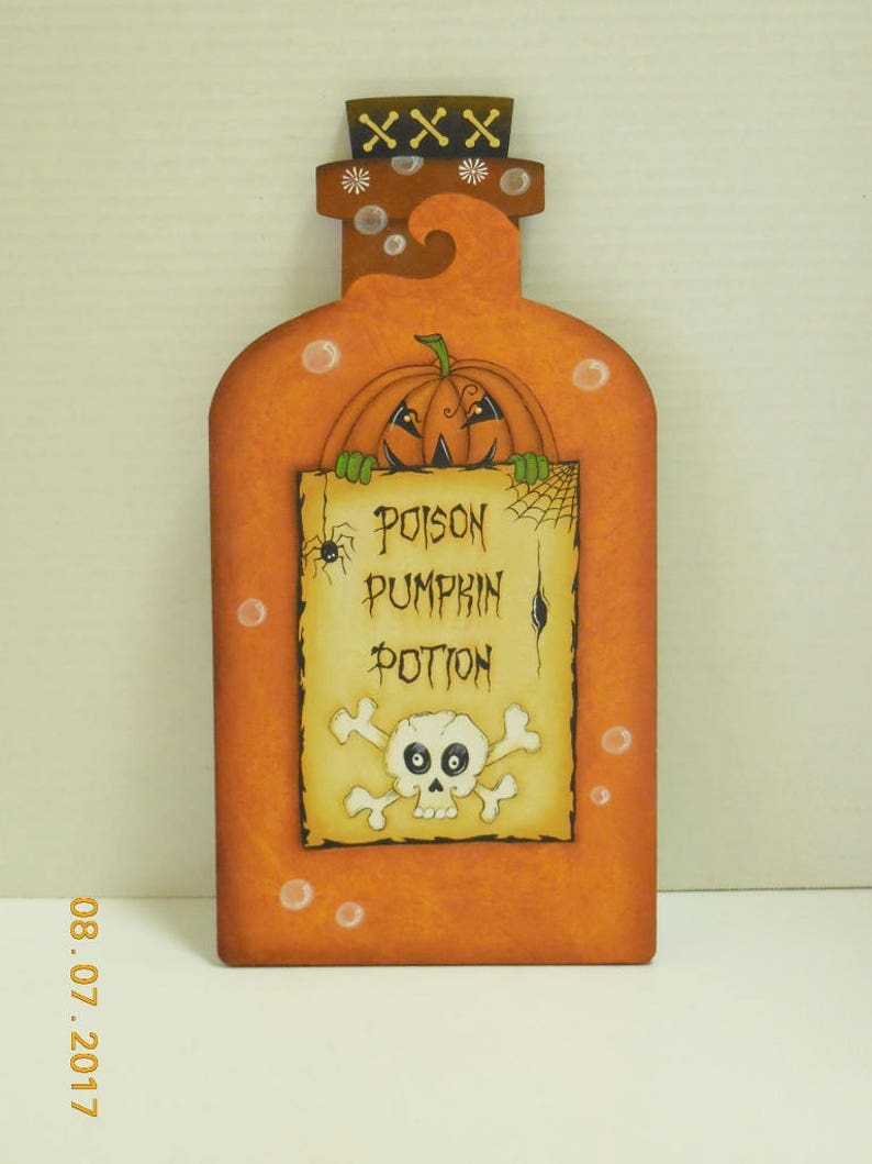 May include: Orange pumpkin shaped bottle with a skull and crossbones and the text "Poison Pumpkin Potion" on a label. The bottle has a cork stopper with a white cross on top.