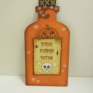 May include: A wooden orange bottle with a pumpkin face and a sign that reads "Poison Pumpkin Potion" with a skull and crossbones.