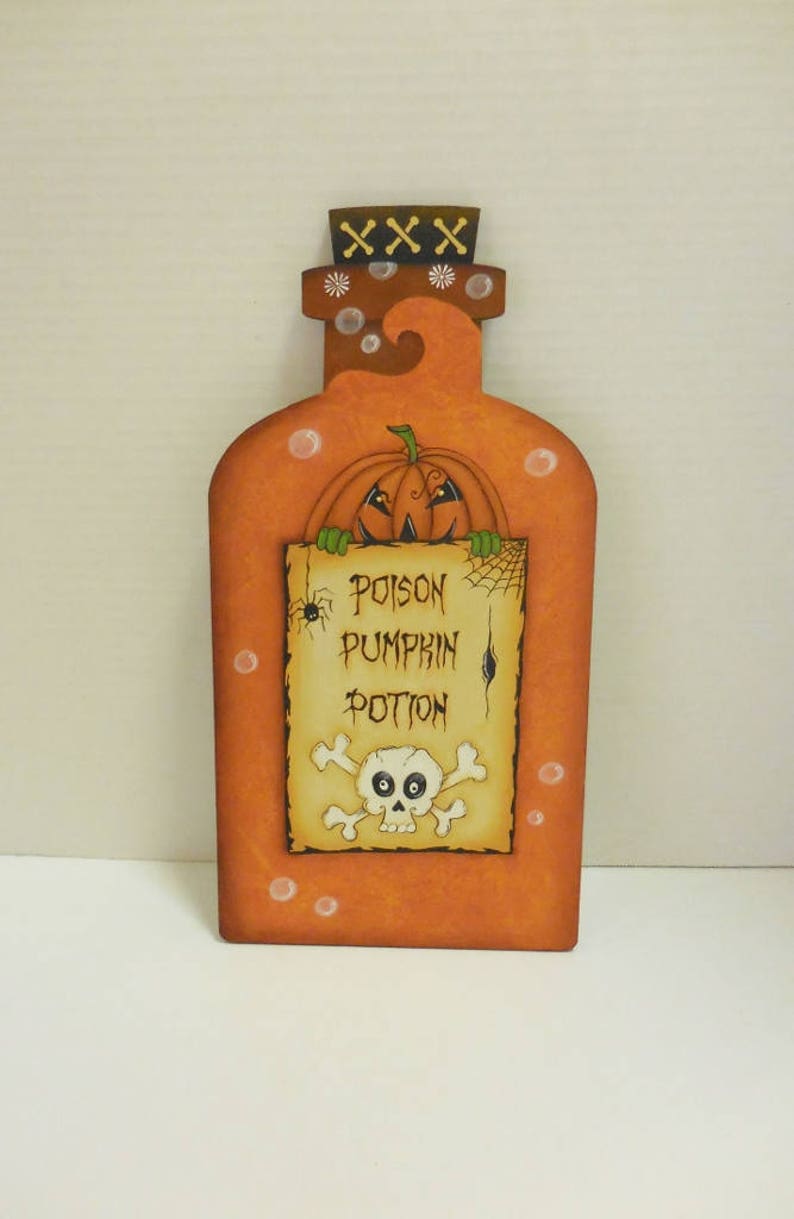 May include: A wooden orange bottle with a pumpkin face and a sign that reads "Poison Pumpkin Potion" with a skull and crossbones.